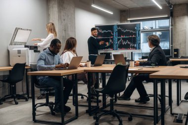 Dizüstü bilgisayarlar masada. Bir grup ofis çalışanı içeride birlikte..
