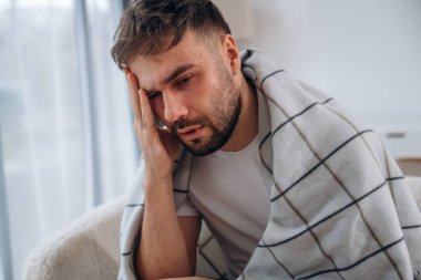 Yorgun, mutsuz yüz ifadesi. Hasta adam evde kendini kötü hissediyor..