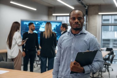 Siyah adam not defteriyle birlikte. Bir grup ofis çalışanı içeride birlikte..