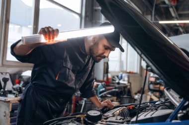 Kaputun altındaki yeri aydınlatıyordum. Araba tamirhanesinde çalışan bir tamirci..