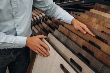 Parke renk örnekleri yığını. Hırdavatçıda adamın elinin detaylı yakın görüntüsü..