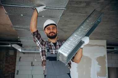 Parçayı tavana yerleştirmeye hazırız. Bir adam bitmemiş bir odayı yeniliyor..