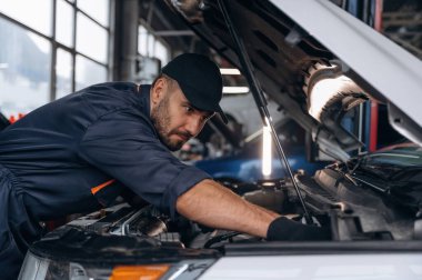 Yandan bak, kaputu aç. Araba tamirhanesinde çalışan bir tamirci..