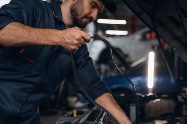 Kablo kurulumu. Araba tamirhanesinde çalışan bir tamirci..