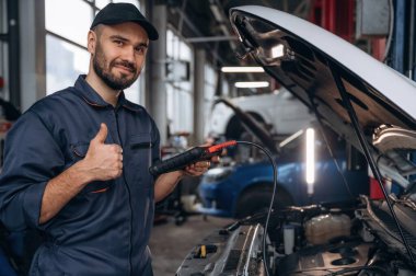 Başparmak yukarı, her şey halledilecek. Araba tamirhanesinde çalışan bir tamirci..