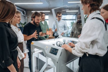 Cihazın nasıl çalıştığını açıklıyorum. Ofiste 3D yazıcının yanında insanlar var..