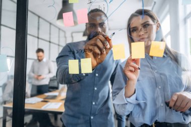 Camdaki kağıt çıkartmaları. Profesyonel işçiler modern ofiste birlikte çalışıyorlar..