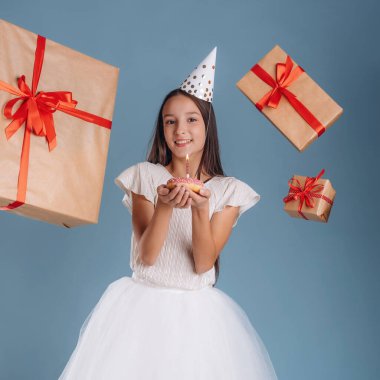 Bir sürü hediye kutusu, mutlu yıllar, mumlu çörek. Beyaz elbiseli genç kız arka plana karşı..