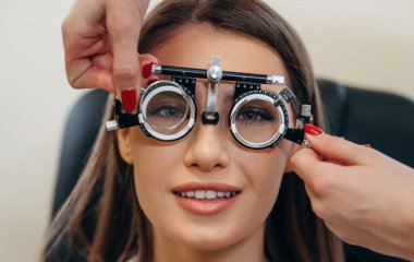 Olumlu yüz ifadesi. Genç kadın göz doktorunun dolabında görüşünü kontrol ediyor..