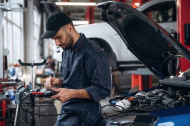 Elektronik ayarlama, dijital tabletle. Araba tamirhanesinde çalışan bir tamirci..