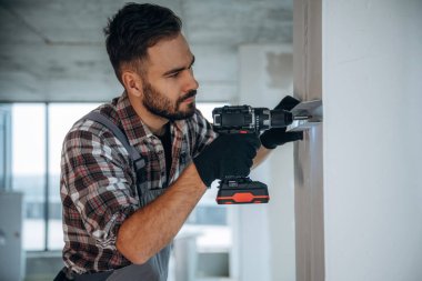 Matkabı kullanarak. Bir adam bitmemiş bir odayı yeniliyor..