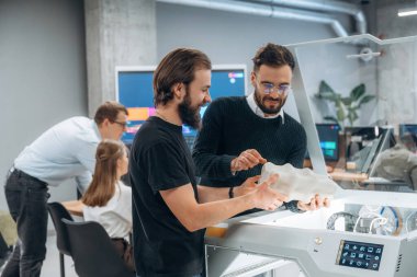 Ayakta. Modern teknoloji. Ofiste 3D yazıcının yanında insanlar var..