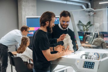 Ayakta. Modern teknoloji. Ofiste 3D yazıcının yanında insanlar var..