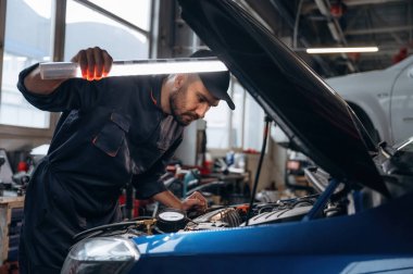 Kaputun altındaki yeri aydınlatıyordum. Araba tamirhanesinde çalışan bir tamirci..