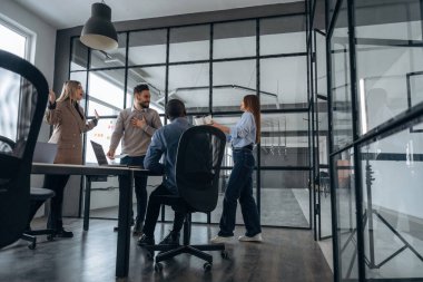 Konuşuyoruz, plan hakkında konuşuyoruz. Profesyonel işçiler modern ofiste birlikte çalışıyorlar..