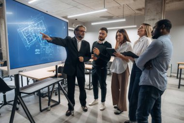 Bina planı ekranda. Bir grup ofis çalışanı içeride birlikte..