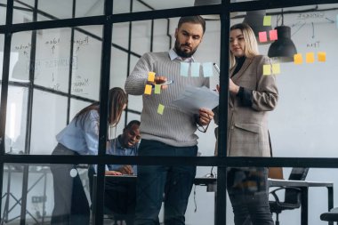 Camda bir sürü çıkartma var. Profesyonel işçiler modern ofiste birlikte çalışıyorlar..