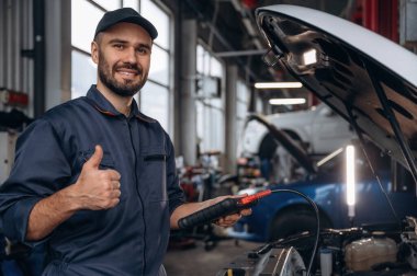 Başparmak yukarı, her şey halledilecek. Araba tamirhanesinde çalışan bir tamirci..