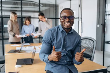 Plana göre, baş parmağını göstermek. Profesyonel işçiler modern ofiste birlikte çalışıyorlar..