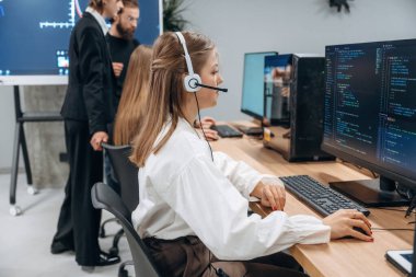 Bilgisayarların başında oturuyor. Tasarımcı takımı ofiste birlikte..