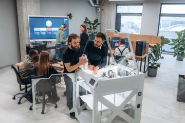 Ofisteki 3D yazıcının etrafında bir grup insan duruyor..