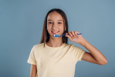 Diş fırçanı tutarak dişlerini temizle. Genç kız arka plana karşı..