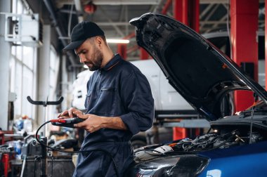 Elektronik ayarlama, dijital tabletle. Araba tamirhanesinde çalışan bir tamirci..