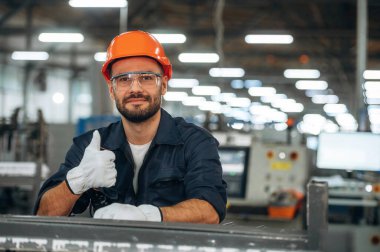 Başparmağımı gösteriyorum. İnsanlar modern fabrikada çalışıyor..