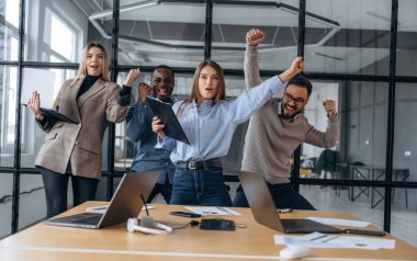 Gülümsüyor, başarıyı kutluyor. Profesyonel işçiler modern ofiste birlikte çalışıyorlar..