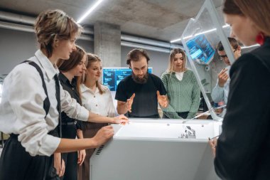 Cihazın nasıl çalıştığını açıklıyorum. Ofiste 3D yazıcının yanında insanlar var..