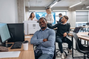 Pozitif siyah adam gülümsüyor. Bir grup ofis çalışanı içeride birlikte..