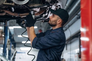 Profesyonel ekipmanlar. Araba tamirhanesinde çalışan bir tamirci..