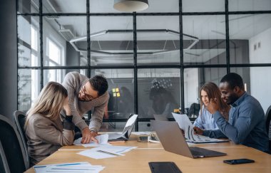 Sakin, masanın yanında oturuyor. Profesyonel işçiler modern ofiste birlikte çalışıyorlar..