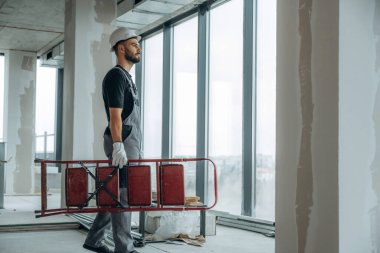 Elinde bir merdiven var. Adam bitmemiş bir odayı yeniliyor..