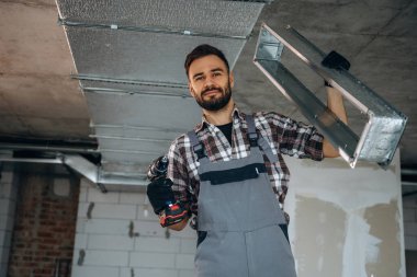 Tavan kuruluyor. Bir adam bitmemiş bir odayı yeniliyor..