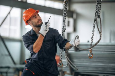 Güçlü kablolar asılıyor. İnsanlar modern fabrikada çalışıyor..