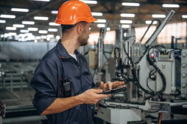 Makine gebeliği, operatör tabletle birlikte. İnsanlar modern fabrikada çalışıyor..