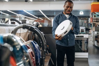 Otomatik elektrikli süpürge ellerinde. Ev gereçleri dükkanındaki adam..