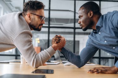 İki ofis çalışanı eğleniyor ve bilek güreşi yapıyor..