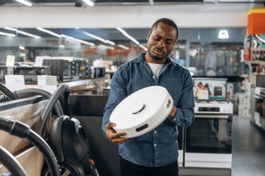 Otomatik elektrikli süpürge ellerinde. Ev gereçleri dükkanındaki adam..