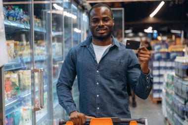 Kredi kartı kullanmak ve elinde tutmak. Erkek müşteri süpermarkette..