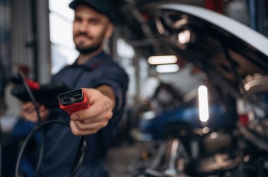 Tableti bağlamak için kablo. Araba tamirhanesinde çalışan bir tamirci..