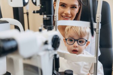 Modern cihazla. Küçük çocuk göz doktorunun dolabını kontrol ediyor..