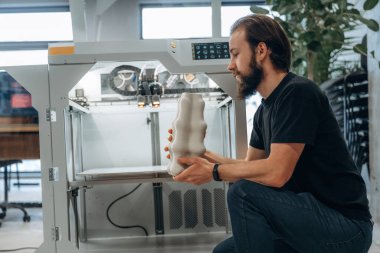 Ürün hazır. Adam 3D yazıcıyla ofiste..