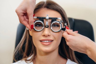 Olumlu yüz ifadesi. Genç kadın göz doktorunun dolabında görüşünü kontrol ediyor..