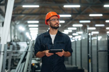 Siyah renkli tablet ellerinde. İnsanlar modern fabrikada çalışıyor..