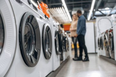 Erkek ve kadın mağazadan çamaşır makinesini seçiyorlar..