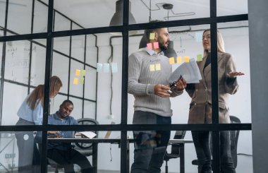 Camda bir sürü çıkartma var. Profesyonel işçiler modern ofiste birlikte çalışıyorlar..