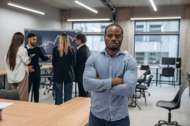 Afrikalı Amerikalı adam meslektaşlarına karşı duruyor. Bir grup ofis çalışanı içeride birlikte..