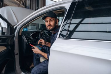 Otomobilde oturmak. Araba tamirhanesinde çalışan bir tamirci..